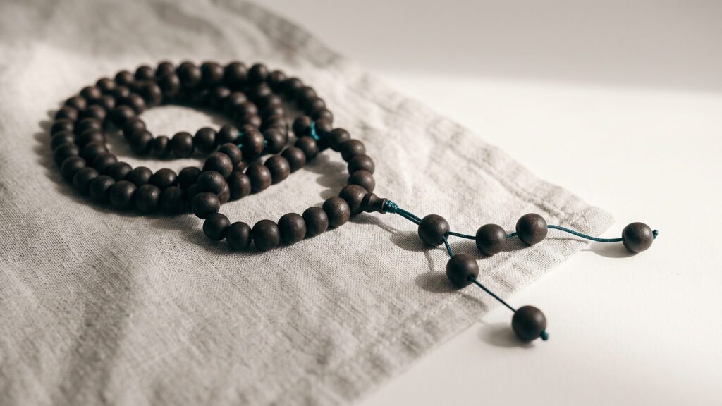 A string of dark prayer beads resting on folded linen cloth