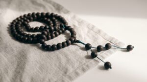A string of dark prayer beads resting on folded linen cloth