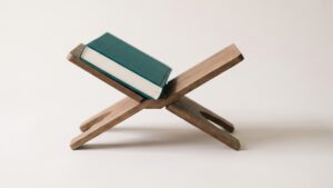 A teal book resting open on a folding wooden book stand