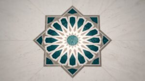 An eight pointed star tile medallion in teal and white set into a plaster wall