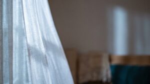 A sheer curtain at a bedroom window in soft early morning light
