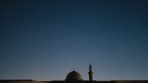 A starlit night sky above the silhouette of a mosque dome and minaret