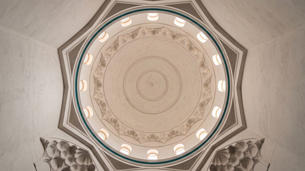 The interior of a mosque dome with concentric plaster mouldings and small windows