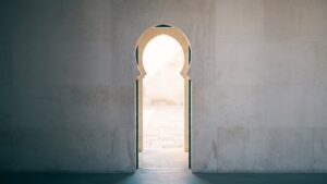 An arched doorway in a plaster wall opening onto bright daylight